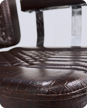 A black leather armchair with dark wood arms in a modern room setting.